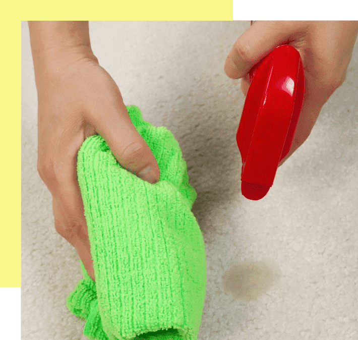 A person holding a red object and cleaning it with green cloth.